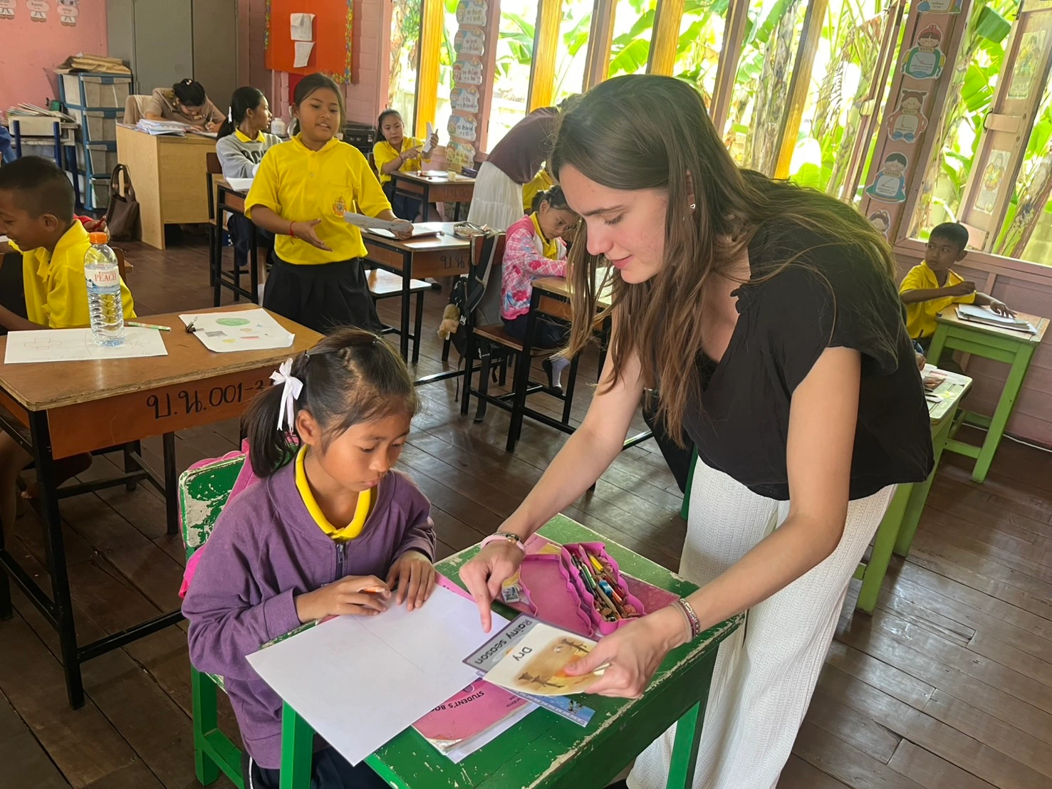 Freiwillige von Abroad Escape unterstützt eine Schülerin in einem Klassenzimmer in Thailand