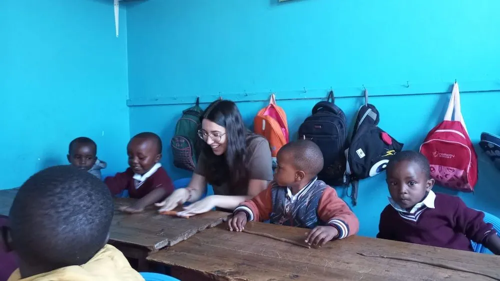 Volunteer helping children with writing activities in a classroom in Tarrafal, showing the childcare and teaching focus of Abroad Escape volunteer programs in Cape Verde.