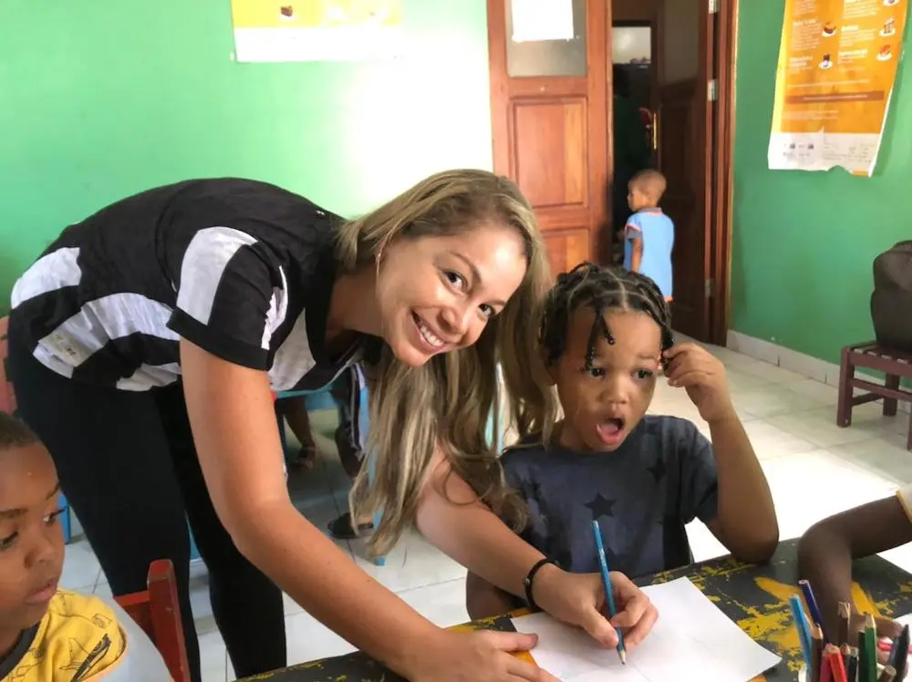 Volunteer helping children with writing activities in a classroom in Tarrafal, showing the childcare and teaching focus of Abroad Escape volunteer programs in Cape Verde.