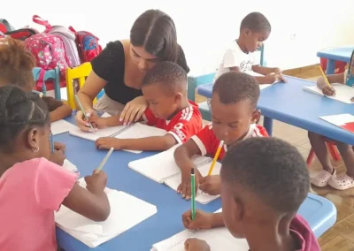 Volunteer helping children with writing activities in a classroom in Tarrafal, showing the childcare and teaching focus of Abroad Escape volunteer programs in Cape Verde.